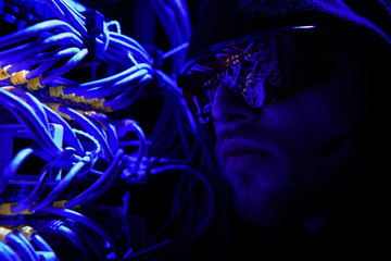 side view of hacker in eyeglasses looking at various wires