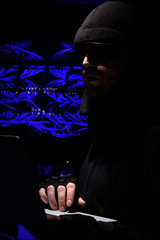 side view of hacker in eyeglasses using laptop with cables on background