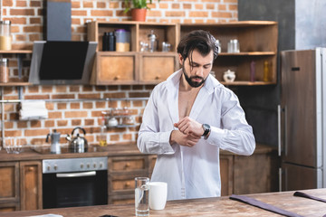 handsome loner businessman checking time in morning at kitchen