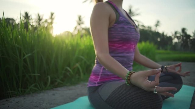 Woman meditating in rice field with hands in mudra at sunrise rapid slow motion