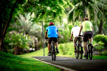 People exercise in the park. (Bicycling, jogging, walking) among green trees and tall buildings in central Bangkok. (Benjakitti Park)