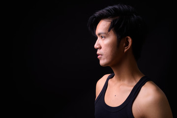 Naklejka premium Young handsome Asian man against black background
