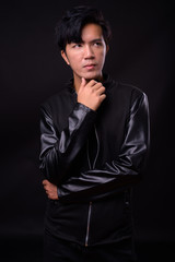 Young handsome Asian man against black background