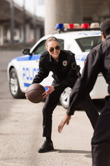 active young police officers playing basketball on street