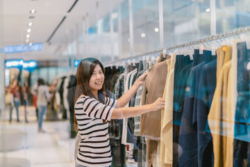 Happy Asian woman choosing clothes in store shop with happy action at department center