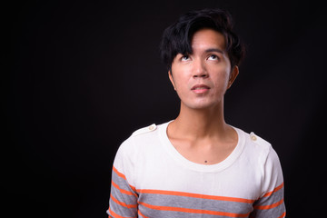 Young handsome Asian man against black background