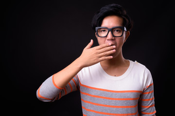 Young handsome Asian man against black background