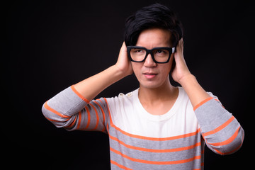 Young handsome Asian man against black background