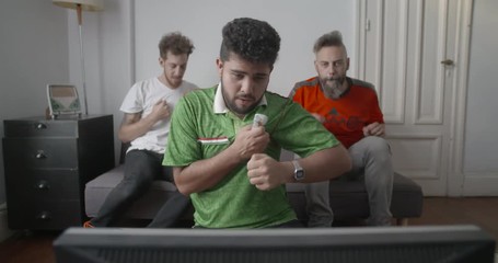 Anxious Mexican football supporters praying while watching football match on television at home
