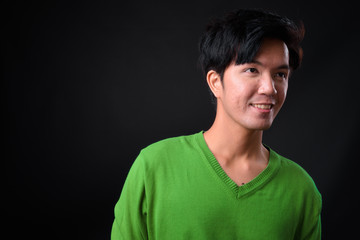Young handsome Asian man against black background