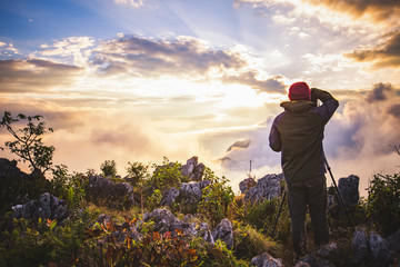Man photographer are shooting a sunset on a mountain landscape.