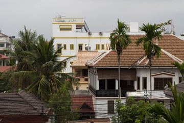 Siem Reap buildings panorama with tile roof top and palm trees. Rooftop view to cambodian city.
