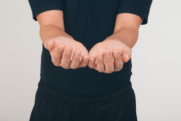 A man in a black t-shirt holds his hands in front of him palms up.