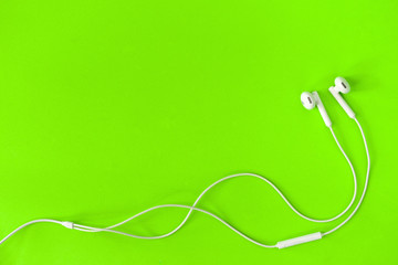 White Earphone on green background, Copy space. Music is my life concept