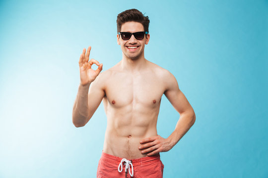 Portrait of a happy young shirtless man in swimming shorts