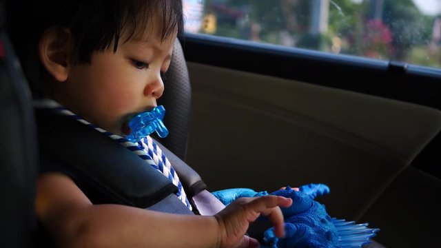 baby sitting on car seat with happy playing toy