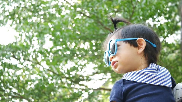 cute baby wearing fashion sunglasses, scene with nature green bokeh background