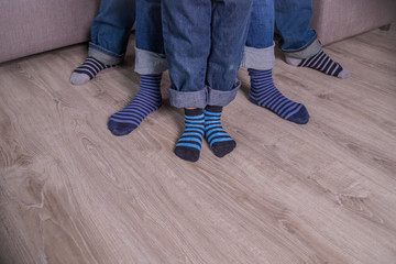 Mother, father and little child wearing blue jeans, blue socks,people legs isolated, body part, family togetherness concept.Feet family mom dad son on wooden background