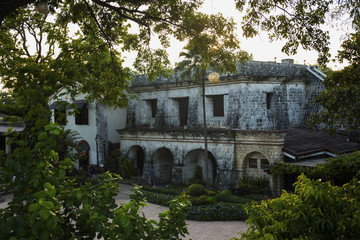 Obraz premium Old historic house view through tropical plants. Fort San Pedro view in sunset. Oldest historical fort in Philippines.