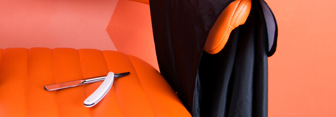 on an orange leather armchair, lies a knife and an apron for cutting hair