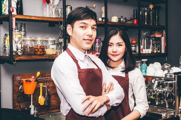 Portrait of couple barista working and standing behind the counter bar in a cafe