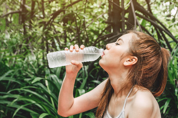 Beautiful woman drinking water on green natural fresh air.Healthy lifestyle concept