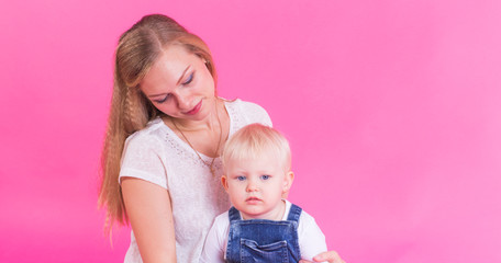 happy little girl and her mother having fun over pink background