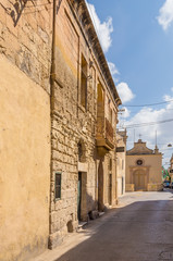 Fototapeta na wymiar Naxxar, Malta. The facade of the ancient building and the chapel of St. Lucy in the background