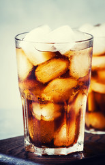 Alcoholic cocktail of rum-cola with ice, gray background, selective focus