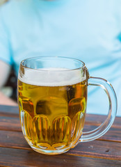 Mug of light beer is on a wooden table in a tavern