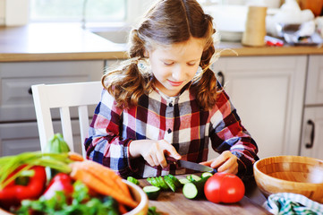 8 years old child girl help mom to cook vegetable salad at home. Healthy eating, little helper concept