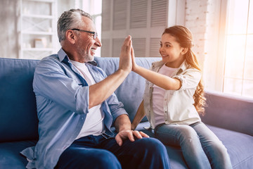 The happy girl and a grandfather greeting on the sofa