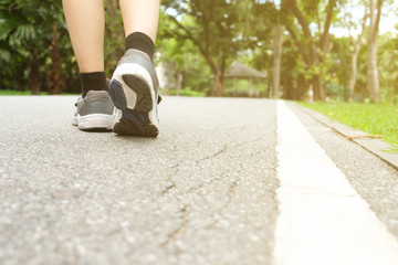 A woman jogging in the park in the evening light.