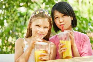 Zwei Mädchen trinken gesunden Orangensaft