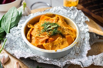 Vegetarian and vegan pumpkin casserole with dill, parsley, onion, garlic and spinach in backing dish. Healthy food concept.