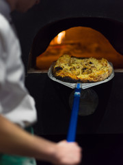 chef removing hot pizza from stove