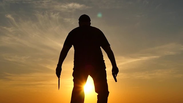 Man with pistol and knife surrender - hands up slow motion silhouette