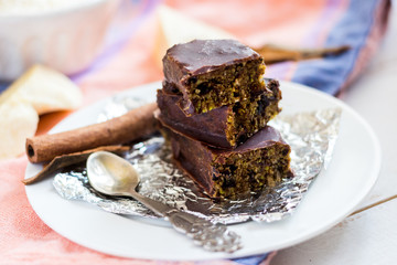 Raw vegan chocolate energy bars. Dates, nuts, cocoa, honey. Served on white plate.