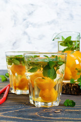 Summer cold drinks. Delicious refreshing drink with apricot and mint in glasses on a wooden table. Compote of fruits. Selective focus.