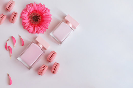 Beautiful perfume bottle with pink flowers and macaroons.  Luxury perfumery background with copy space. Sweet and Floral fragrance concept.