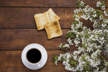 Obraz na płótnie Canvas Toast, coffee and blossoming cherry branches on a wooden background.