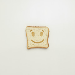 Slice of toast with cheerful smile on white background.