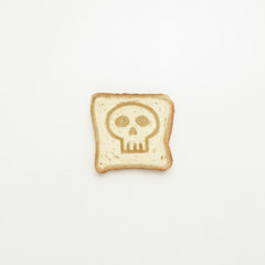 Slice of toast with skull on white background.