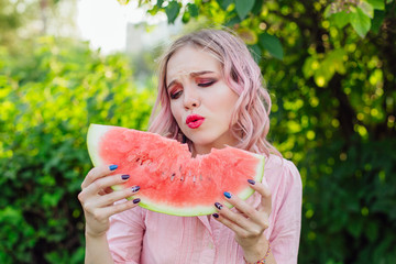 Beautiful young woman with pink hair enjoying watermelon