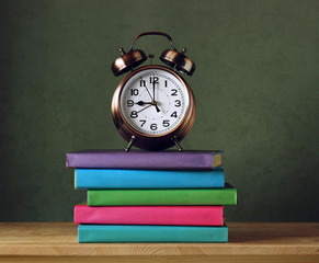 Back to school. Alarm clock and textbooks in colored covers.