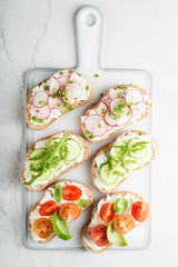 Different sandwiches with vegetables on a light gray background. top view.