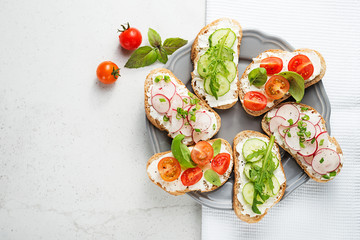 Different sandwiches with vegetables on a light gray background. top view.