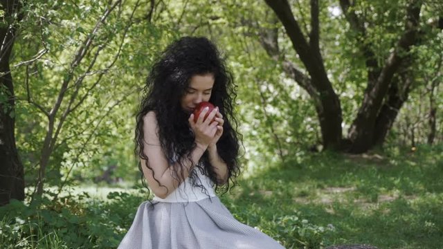 Beautiful woman in blue dress enjoy a smell of fresh red apple