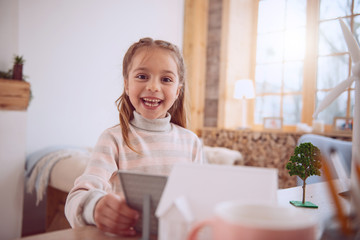 Wonderful mood. Cheerful happy girl looking at you while holding a solar battery