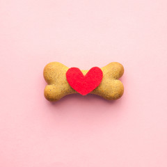 bone-shaped biscuit for dog and red heart on pink background, concept pet care